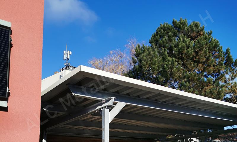 Anlehncarport aus feuerverzinktem Stahl mit Trapezblech-Pultdach und wei&szlig;er Randblende am Wohnhaus
