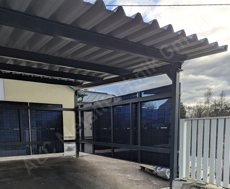 Stahl&uuml;berdachung in Anthrazit mit Trapezblech-Pultdach &uuml;ber verglasten Abstellboxen einer Wohnanlage