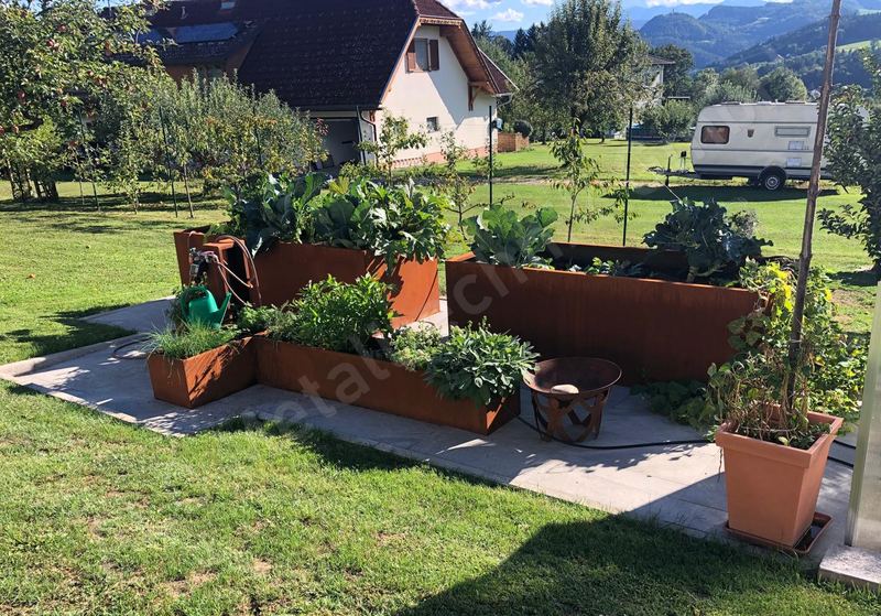 Hochbeetanlage aus Cortenstahl mit Feuerschale und Kr&auml;uterbeeten im Garten mit Bergblick
