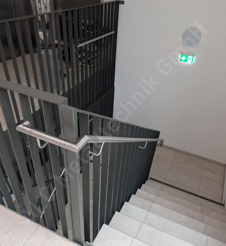 Treppengel&auml;nder aus anthrazitem Flachstahl mit Edelstahl-Handlauf im Stiegenhaus
