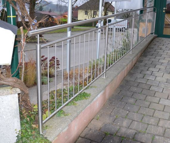 Gel&auml;nder aus Edelstahl entlang einer gepflasterten Rampe vor einem Wohnhaus