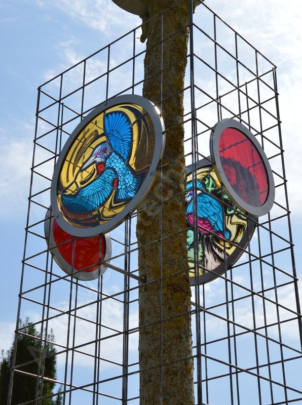 Rank- und Rosengitter aus Stahl rund um einen Baumstamm, mit runden Glasbildern als dekorative Einsätze