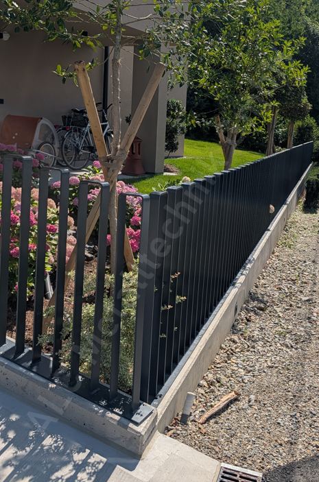 Anthrazitfarbener Stabzaun auf Betonsockel entlang der Einfahrt eines Einfamilienhauses